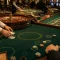 A player studies casino game options on a laptop in a dimly lit gaming room.